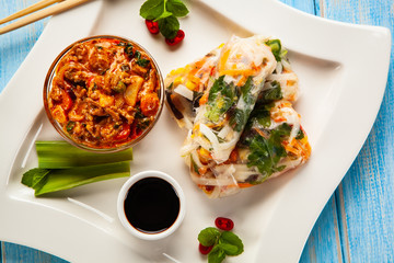 Chinese spring rolls, rice and sauces on wooden table
