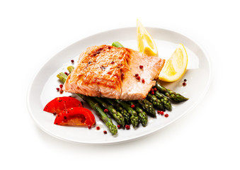 Fried salmon fillet with asparagus, lemon and tomatoes on white background
