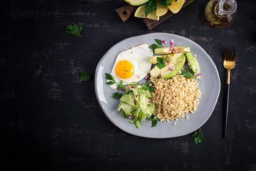 Diet menu. Healthy lifestyle. Bulgur porridge, fried egg and fresh vegetables -  cucumber and avocado on plate. Top view, overhead, copy space