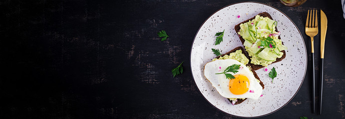 Healthy breakfast. Sandwich with avocado guacamole, cucumber and fried egg,   for healthy breakfast or snack. Top view, overhead, banner