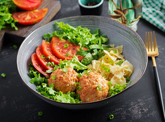 Italian pasta. Farfalle with meatballs and salad on dark background. Dinner. Slow food concept