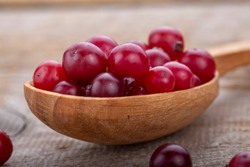 Fresh cranberries in spoon on a wooden table.