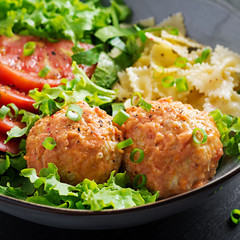 Italian pasta. Farfalle with meatballs and salad on dark background. Dinner. Slow food concept