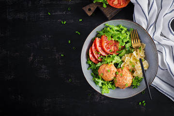 Italian pasta. Farfalle with meatballs and salad on dark background. Dinner. Top view, overhead. Slow food concept