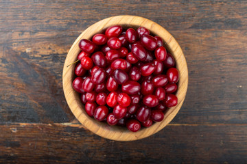 Dogwood in a plate on a wooden background. Gathering the summer harvest.