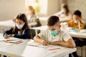 Elementary students with protective face mask back at school after coronavirus epidemic.