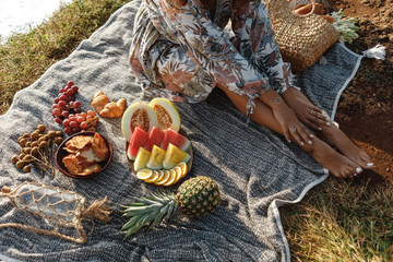 Picnic set with tropical fruits. Beautiful summer background with girl and products on the blanket, summertime - Powered by Adobe