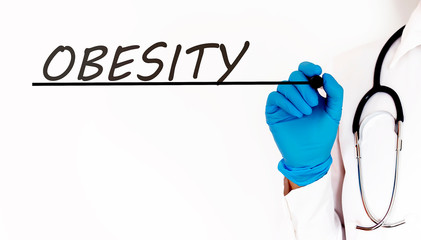 Doctor writing word OBESITY . Medical concept on white background