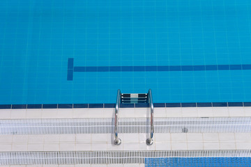 Empty sports swimming pool. Swimming pool edge with a steel ladder. Top view Horizontal orientation