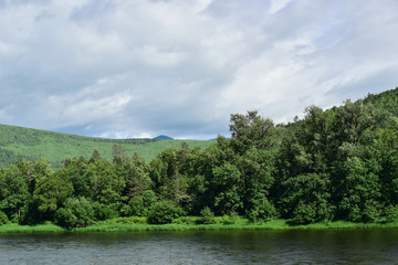 Fototapeta na wymiar River and forest. Green hills and cloud cover. The Anyui river, the mountains of Sikhote-Alin.