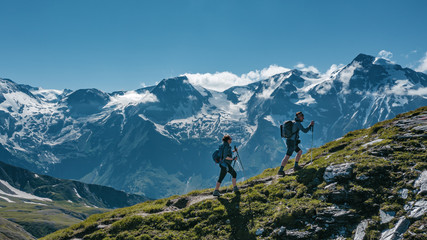 Two young hikers walking up a mountain in Austria, with scenic views on the background