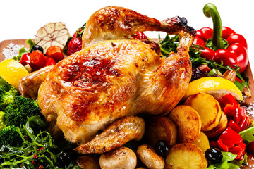 Roast chicken with vegetables served on cutting board on white background
