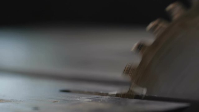 Close up rotating of circular saw on a metal table in a woodworking workshop at a small furniture manufactory at 200 fps slow motion. Woodworking, joinery