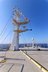 Ship structures, masts, antennas, funnel, ship wheelhouse against the blue sky and clouds. Vessel traveling at ocean. © masterskuz55