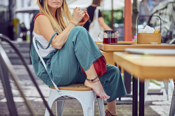 ?ropped photo of beautiful red-haired girl holding a cup of tea outdoors