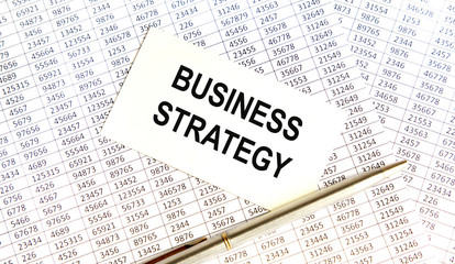 Fototapeta premium Wooden picture frame with inscription 'business strategy' on beautiful background from dollar bills and metalic pen. Business concept.