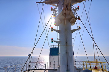Ship structures, masts, antennas, funnel, ship wheelhouse against the blue sky and clouds. Vessel traveling at ocean. © masterskuz55