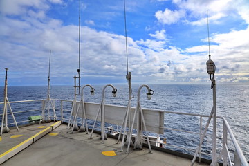 Ship structures, masts, antennas, funnel, ship wheelhouse against the blue sky and clouds. Vessel traveling at ocean. © masterskuz55