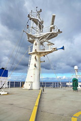 Ship structures, masts, antennas, funnel, ship wheelhouse against the blue sky and clouds. Vessel traveling at ocean. © masterskuz55