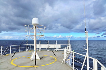 Ship structures, masts, antennas, funnel, ship wheelhouse against the blue sky and clouds. Vessel traveling at ocean. © masterskuz55