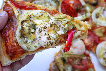 A slice of pizza seafood spicy on asian woman hand , food background