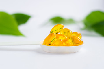 Capsules of vitamin A and E, Golden fish oil in a spoon. Nutritional supplements for good health on a white background. Supplementary feeding. Omega-3. Concept of health and healthy nutrition