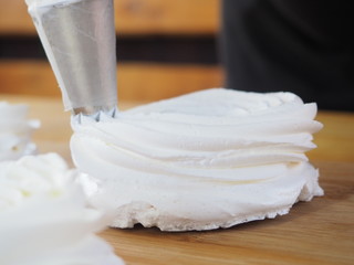 the pastry chef squeezes cream on the cakes. cream on meringue. preparation of dessert.