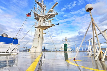 Ship structures, masts, antennas, funnel, ship wheelhouse against the blue sky and clouds. Vessel traveling at ocean. © masterskuz55