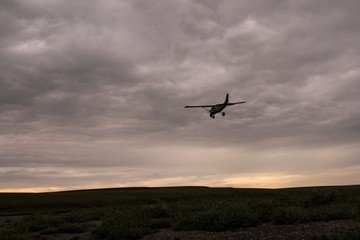 Fototapeta na wymiar Der letzte Flug - Landendes Buschflugzeug bei Sonnenuntergang - Alaska