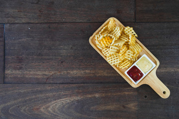 French fries served with ketchup on the wooden desk.