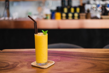A glass of Mango Smoothies, refreshing beverages,  serve on the wooden desk.