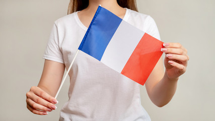 France flag. European culture. Woman holding official national symbol tricolor with three vertical bands stripes blue white red isolated on blur neutral background. Vacation travel.