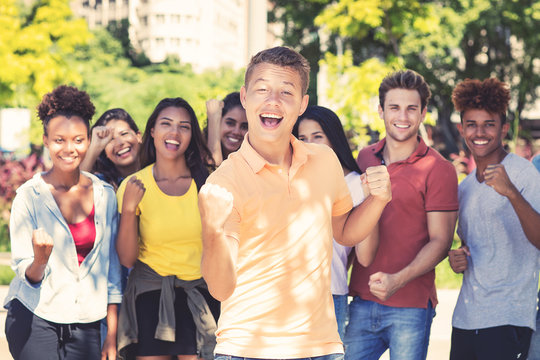 Young male student with group of cheering young adults