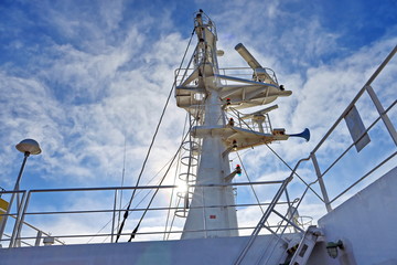 Ship structures, masts, antennas, funnel, ship wheelhouse against the blue sky and clouds. Vessel traveling at ocean. © masterskuz55