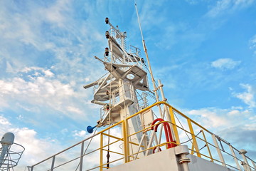 Ship structures, masts, antennas, funnel, ship wheelhouse against the blue sky and clouds. Vessel traveling at ocean. © masterskuz55