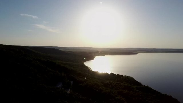 Aerial video of a lake in the mountains at sunset on a sunny summer warm day. Morning or evening in the mountains