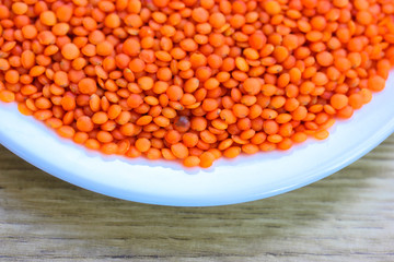 Red lentils in a round white plate: ingredients for a healthy diet natural meal