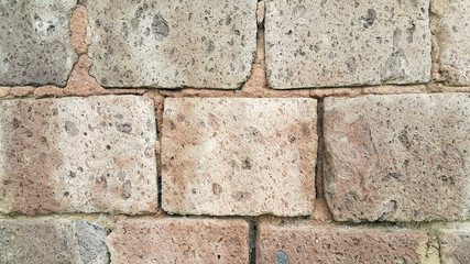 Brown-orange wall. Old tuff stone wall. You can see the ground between the stones. Background drawing.