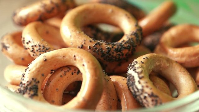 Fresh toasted appetizing bagels with poppy seeds in a saucer rotate. Fresh bakery