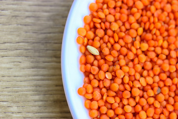 Red lentils in a round white plate: ingredients for a healthy diet natural meal