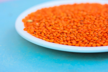 Red lentils in a round white plate: ingredients for a healthy diet natural meal