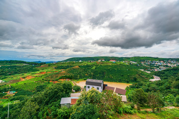 Fototapeta na wymiar Small village in a tea hill valley on a stormy day in the highlands of Da Lat, Vietnam. The place provides a great deal of tea for the whole country