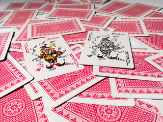 Two jokers from a deck of playing cards on a pile of cards with a red back.