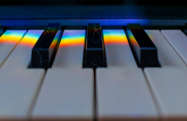 A dusty musical keyboard with rainbow reflections on it