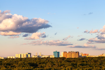 Fototapeta na wymiar sunset blue and pink sky with and gray clouds over city and green forest in sunny summer evening
