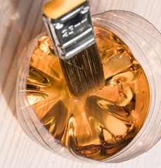 Brush for coloring wood. Dip the brush in a jar of varnish. Paint a wooden table with a brush, wood work in the workshop. Hobbies and manual work.