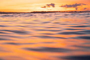 Water surface. View of a Sunset sky background. Dramatic gold sunset sky with evening sky clouds over the sea. View of a Crystal clear sea water texture. Landscape. Small waves. Water reflection