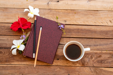 Naklejka na ściany i meble notebook planner for business work with hot coffee, red flowers hibiscus , white flowers frangipani arrangement flat lay style on background wooden