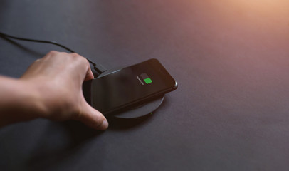 
Hand that connects the phone to the wireless charger. Modern technology concept.