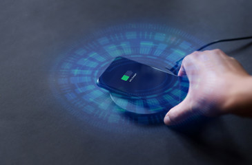 Hand that connects the phone to the wireless charger. Modern technology concept.